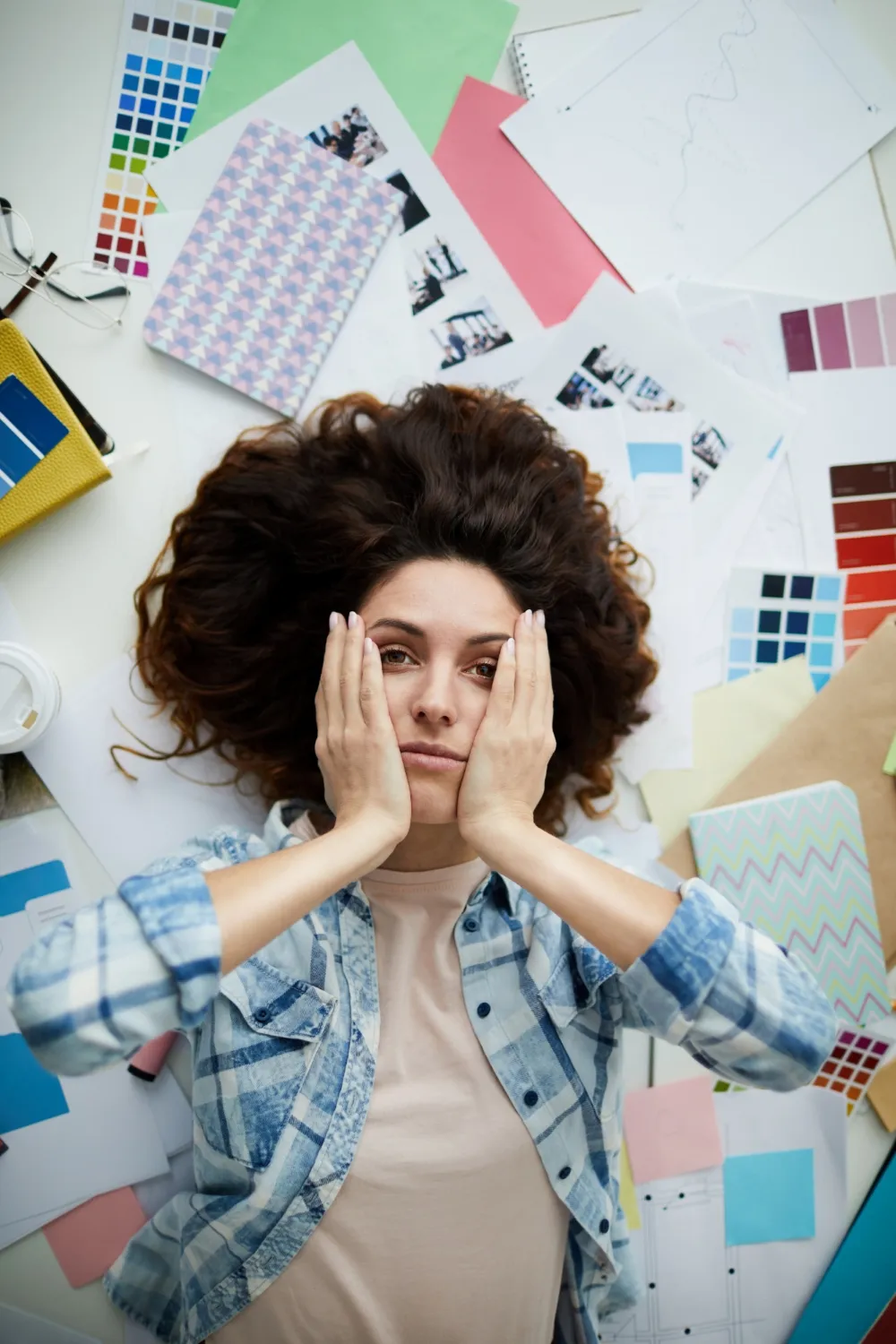person lying on paper covered floor and stressed out